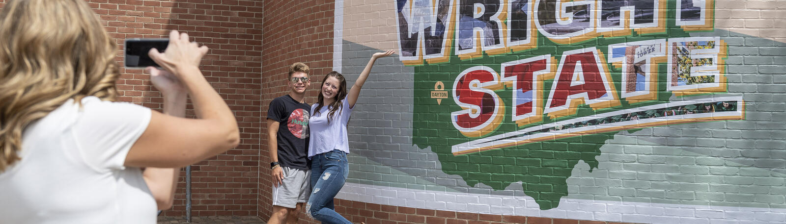 photo of people taking a photo in front of the welcome to wright state mural